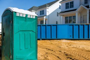 Porta potty on a job site next to a dumpster